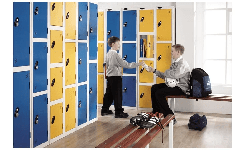Two schoolboys placing folders and a football into blue and yellow steel workplace lockers